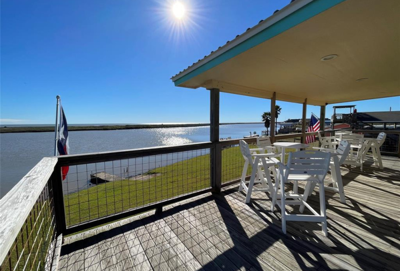 This photo showcases a spacious waterfront deck with a stunning view of the ICW under a clear blue sky. The deck features seating areas perfect for relaxing or entertaining, and it offers a peaceful, scenic atmosphere.