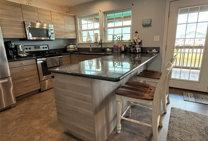 Beautiful kitchen granite countertop. Natural light flows, in the morning with glistening water reflections through the windows and glass door, creating a bright and inviting space.