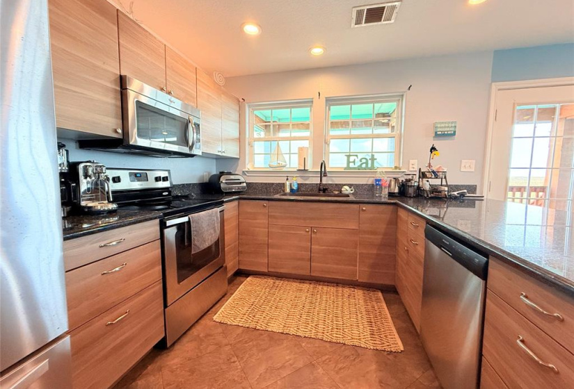 This kitchen has a cozy U-shaped layout with ample natural light from two large windows.