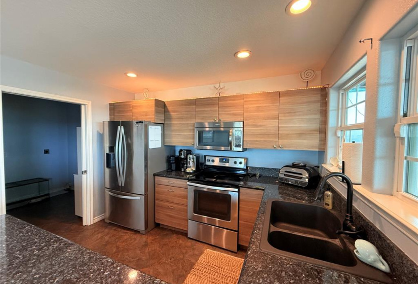 Features a double-door fridge, built-in microwave, and a window above the sink for natural light and tranquil water views.
