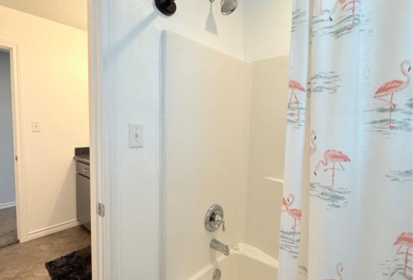 This bathroom features a clean, white tub and shower combo with a playful flamingo-themed curtain.