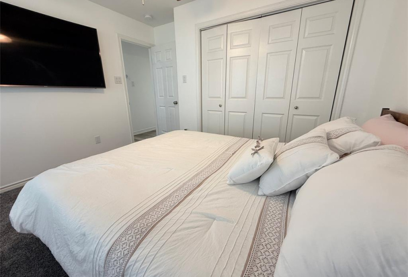 This same bedroom offers a large wall-mounted TV, a comfortable bed with decorative pillows and a spacious closet with sliding doors in addition to a beautiful bay window overlooking the pool area.