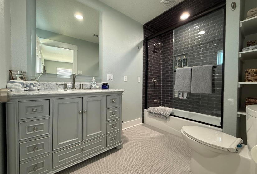 Modern master bathroom featuring a sleek vanity with ample storage, large mirror, and a stylish glass-enclosed shower with dark subway tiles. Bright and inviting space with neutral tones and contemporary fixtures.