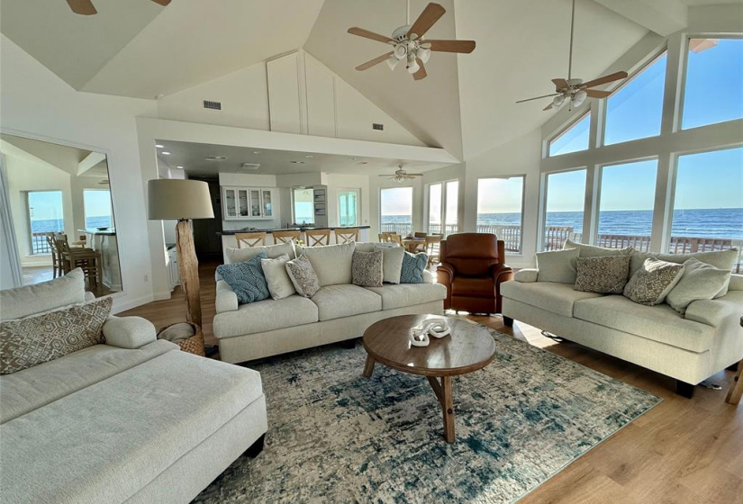 Living room includes vaulted ceiling, comfortable seating, a stylish rug, and ceiling fans, creating an inviting atmosphere perfect for relaxation and entertaining.