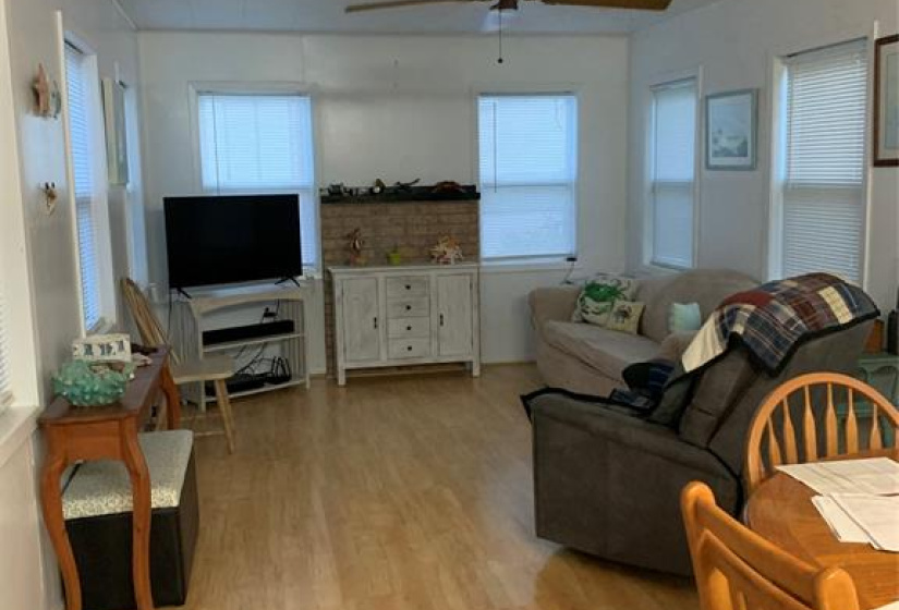 The living room features a ceiling fan and large windows.