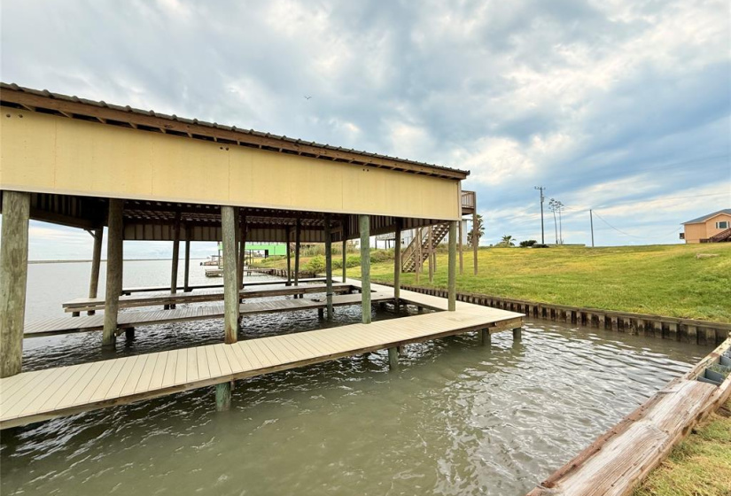 This photo showcases a waterfront property with a covered dock, perfect for boating enthusiasts. The area features a spacious platform over the water and a grassy bank, offering scenic views and outdoor relaxation space.