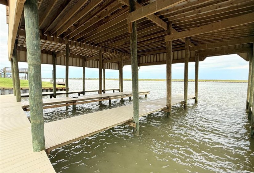 This photo showcases a waterfront property with a covered dock extending over calm waters, offering serene views and easy access for boating or fishing activities.
