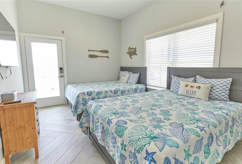 First bedroom features windows, access to the outdoor balcony, and beautiful flooring.
