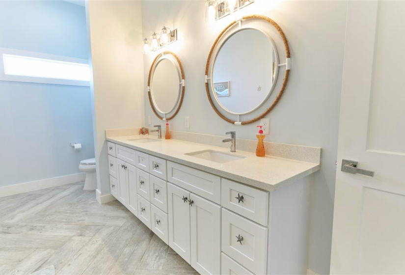 First bathroom features double sinks, custom paint, and white cabinets.