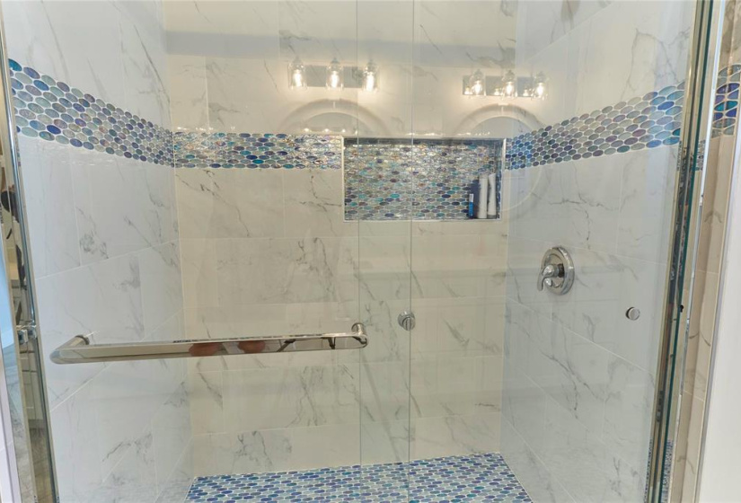 The first bathroom has a walk-in shower with glass door and tile surround.