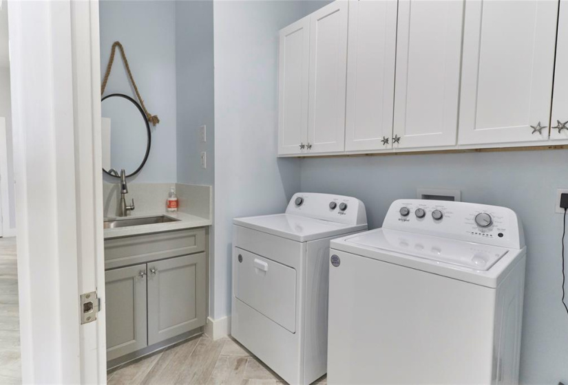 Laundry room features washer and dryer connections, custom paint, storage space, and a stainless steel sink.
